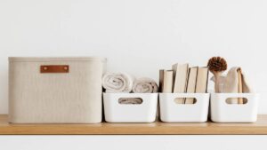 Aufgeräumtes Regal mit weißen Aufbewahrungsboxen, zusammengerollten Handtüchern und sortierten Büchern – Symbol für Struktur und minimalistisches Wohnen.