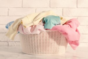 Wäschekorb mit bunter Kleidung vor einer hellen Wand